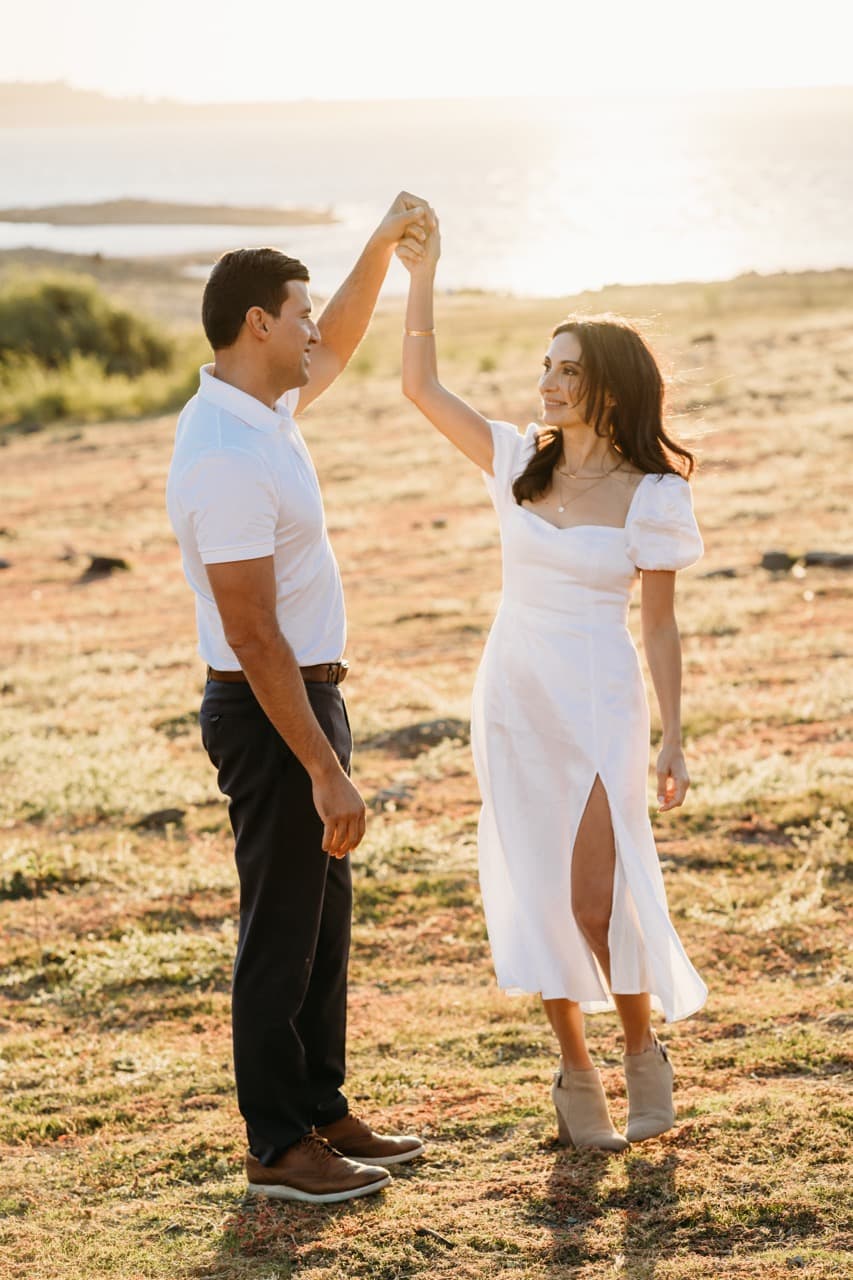Couple dances, he in a white polo raising his hand to twirl her in white
