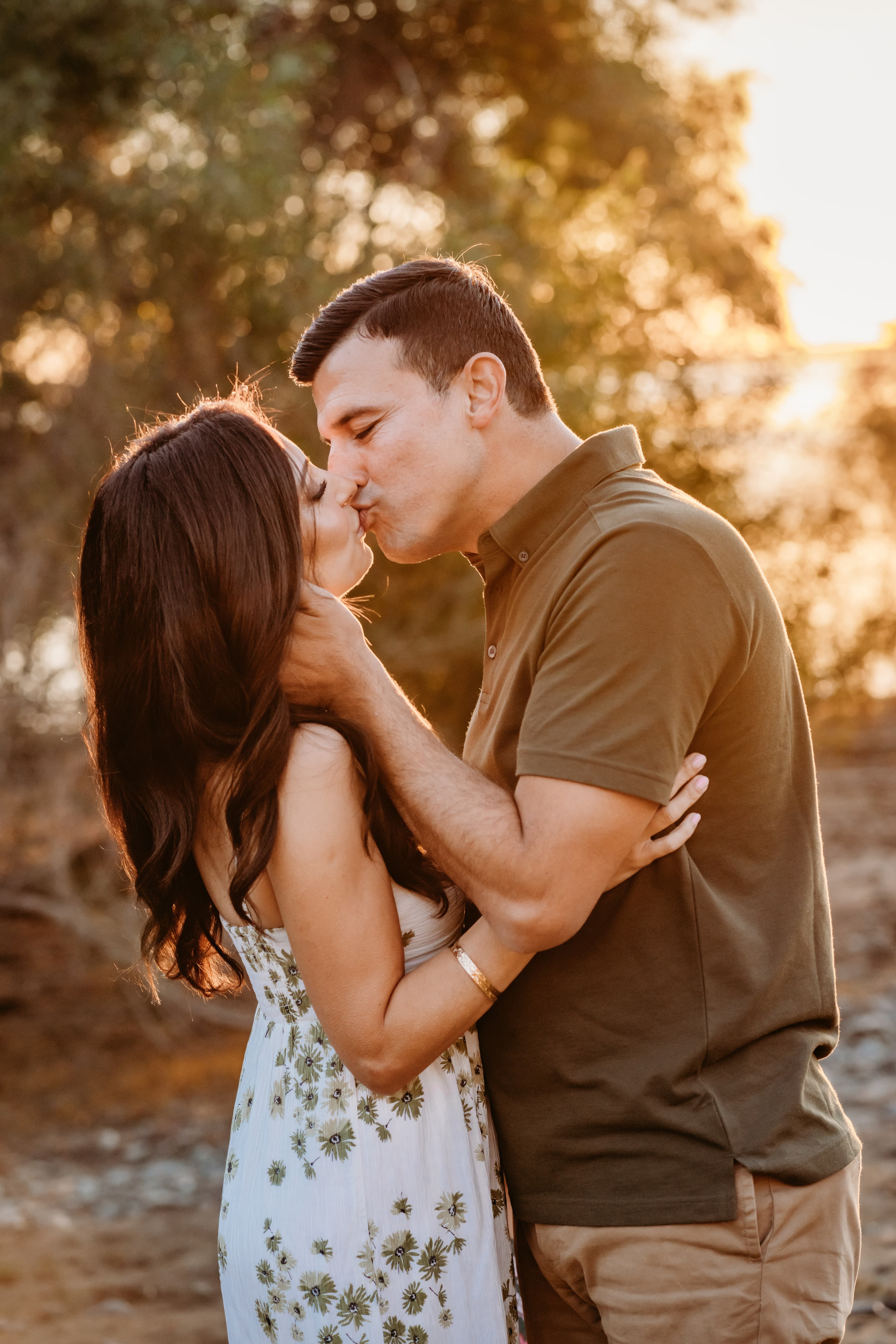 Couple shares a kiss surrounded by soft golden-hour bokeh light
