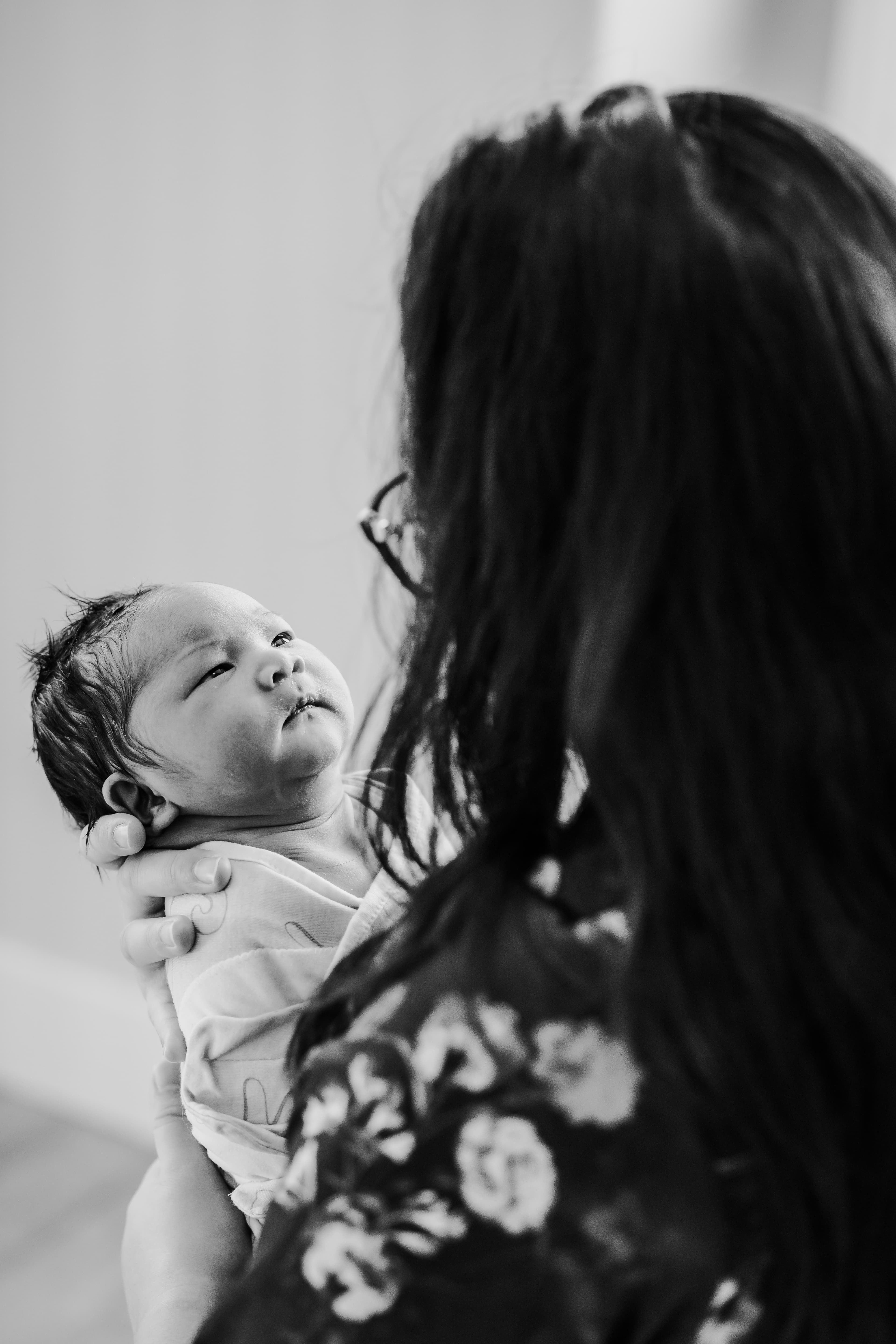 Black-and-white portrait of a mother gazing at her newborn held face to face
