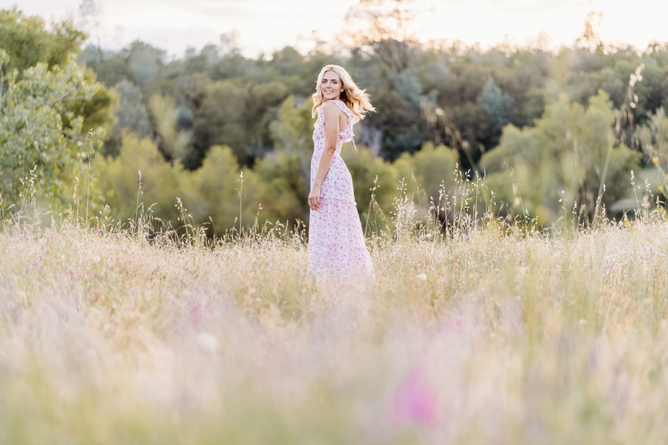 Woman in a pink floral dress in a wildflower field